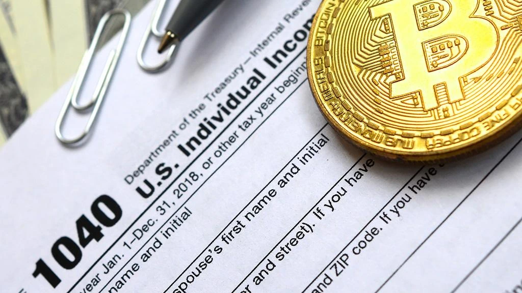 Cryptocurrency tax calculation and reporting process with financial documents and laptop